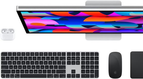 Draufsicht auf einen Studio Display Monitor, ein Magic Keyboard in Schwarz, eine Magic Mouse in Schwarz, ein Magic Trackpad in Schwarz und ein AirPods Case in Weiß