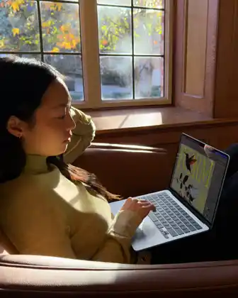 Eine Person sitzt auf einem Stuhl und arbeitet mit einem MacBook Air